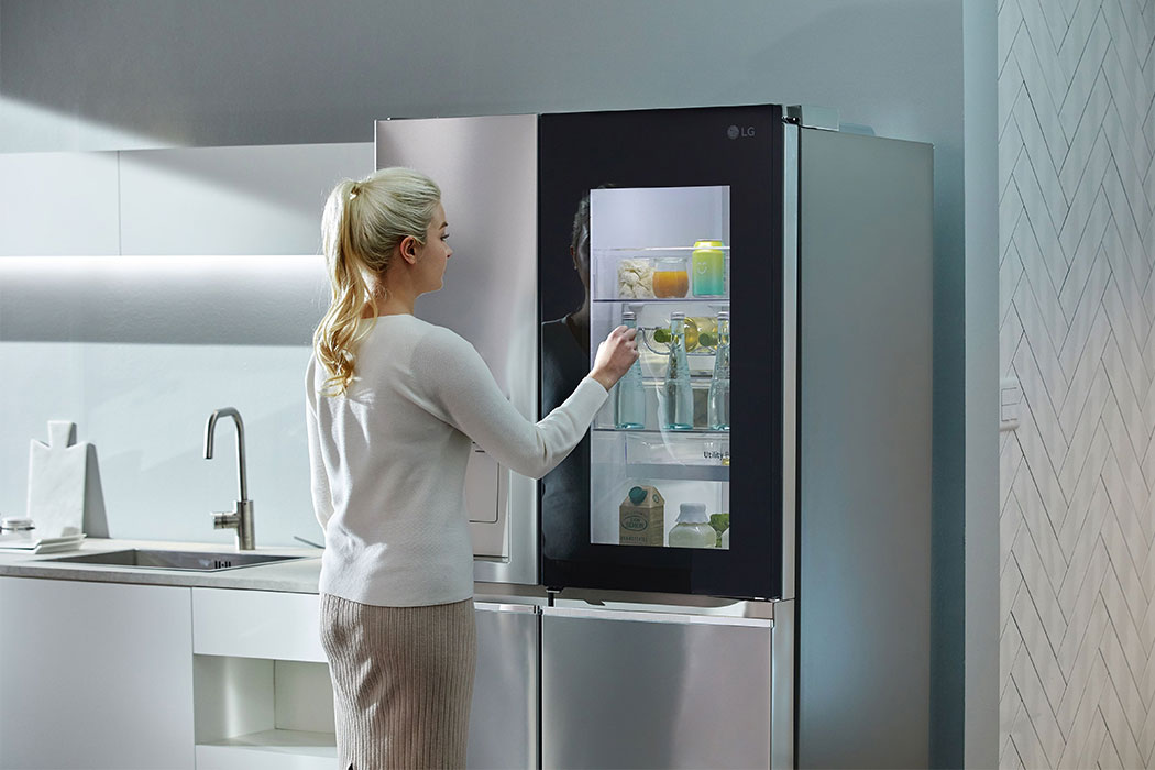 a woman looking inside through a transparent door of LG Dios refigirator aka magic space