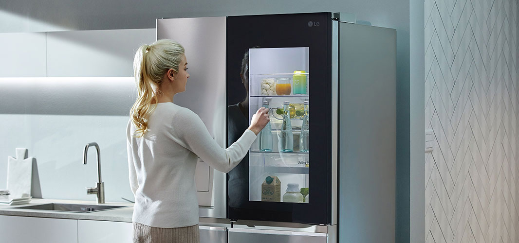 a woman looking inside through a transparent door of LG Dios refigirator aka magic space