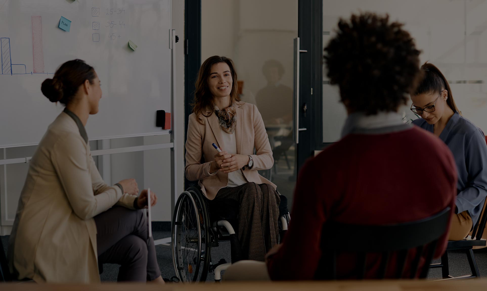 image of some people sitting in chairs and talking with a woman in a wheelchair