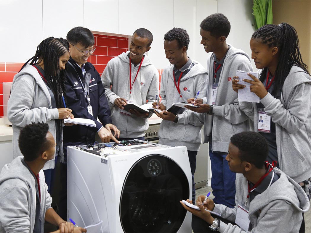 Ethiopian youths in white hoods are practicing maintaining washing machines at LG-KOICA job training school